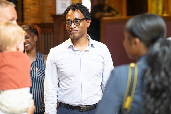 Wesley Bell, wearing a light-colored button up shirt, smiles as he meets with supporters.