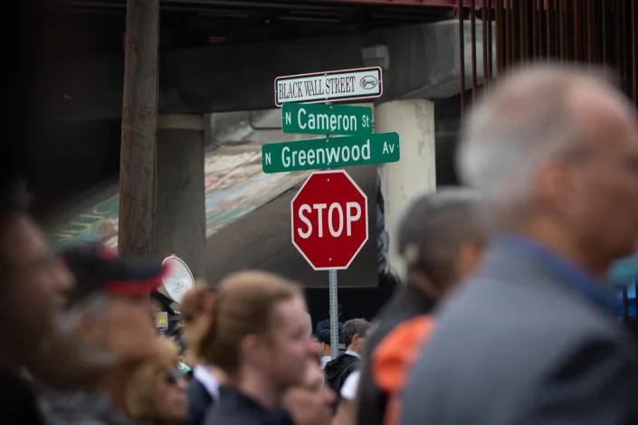 A crowd of mixed ethnicity mills into the intersection of Cameron Street and Greenwood Avenue.